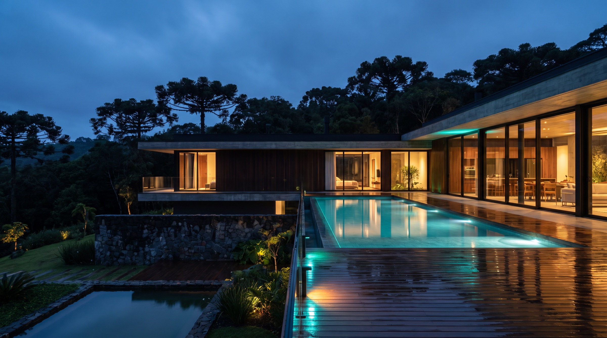 Residência de alto padrão ao entardecer com automação Facsom, piscina iluminada e mata de araucárias ao fundo
